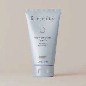 White background with a tube of face reality cran-peptide cream, which is rich and restorative